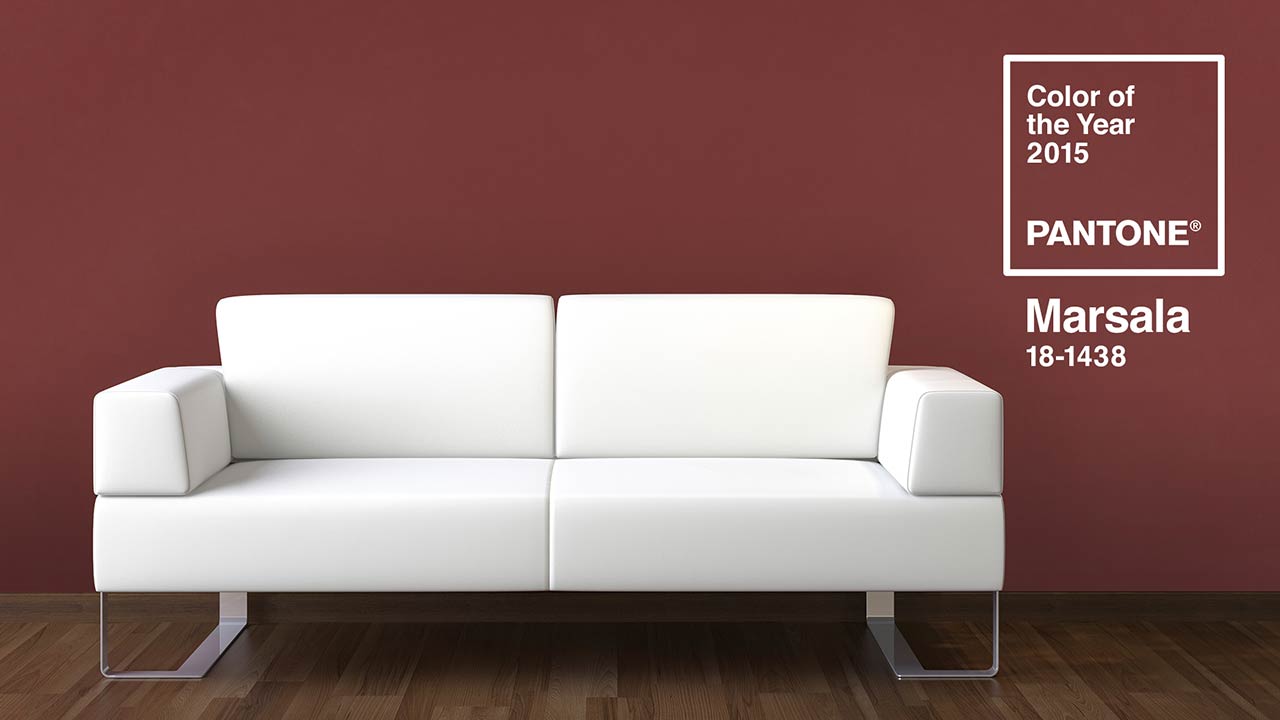 Eine helle Couch vor einer Wand in der Farbe Marsala.