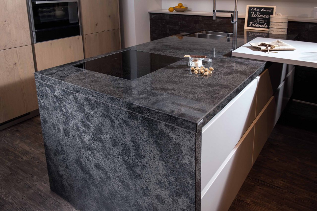Kücheninsel aus grau marmoriertem Naturstein "Manhattan Grey" mit weißer Front und Kochfeld.