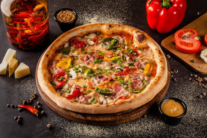 Italienische Pizza mit Gemüse auf einer dunklen Steinplatte
